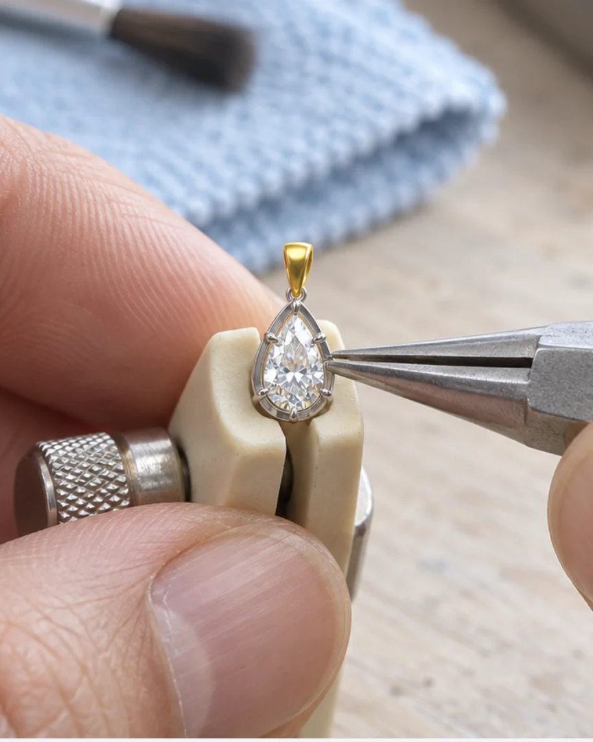 Illustrated finishing scene showing a jeweller working on the edge of this pendant.
